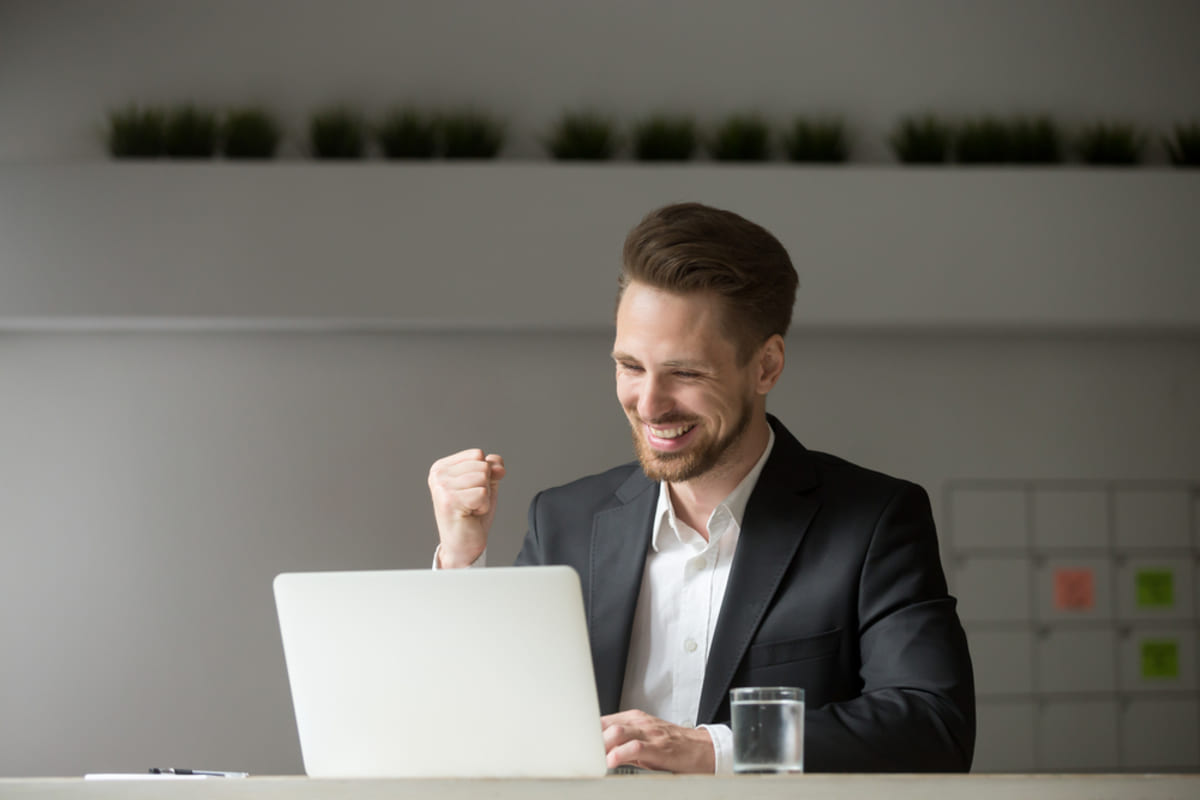 Happy man at his desk celebrating