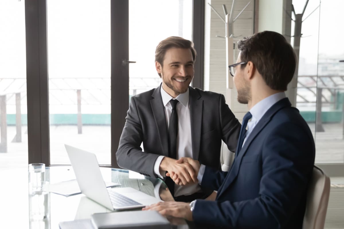 Smiling businessmen shake hands, commercial real estate broker services are an asset concept