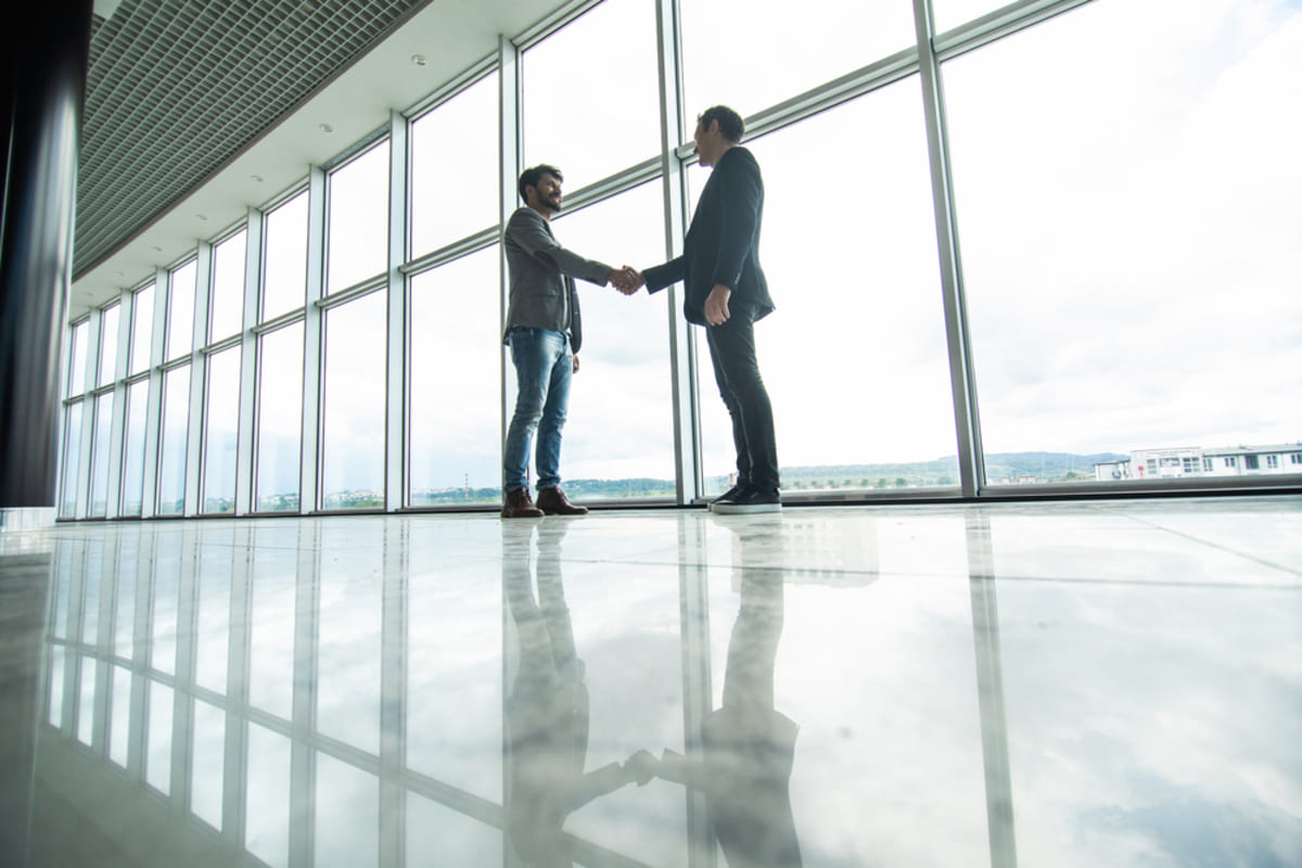 Two businessmen shaking hands in a building, invest in Chicago commercial real estate concept