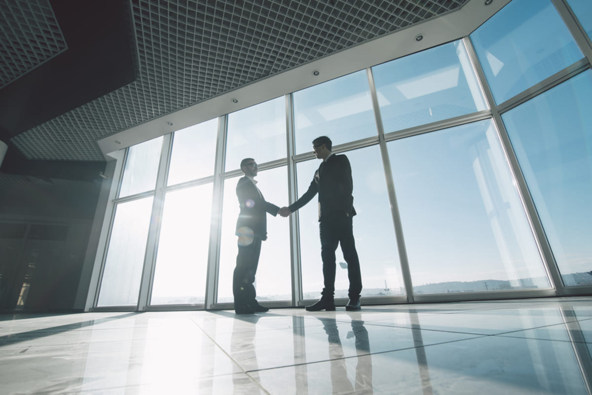 Two people shaking hands in an office space, partnering with a commercial properties management company