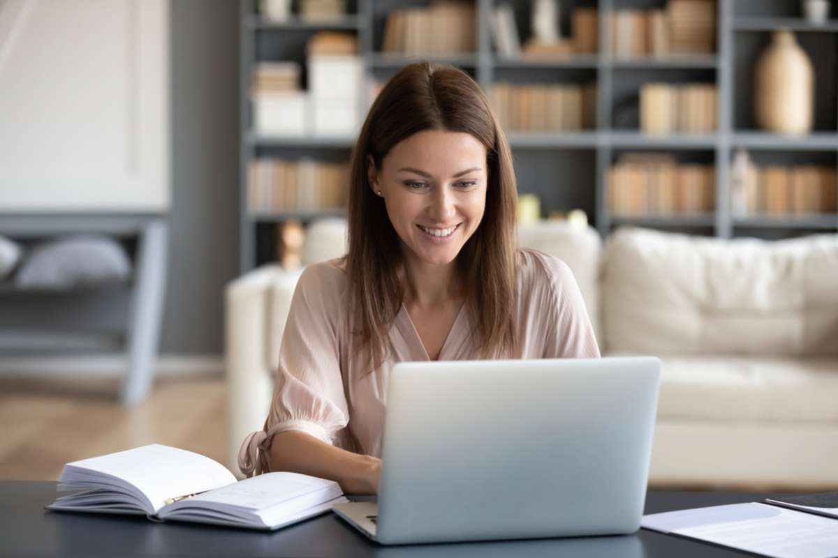 A happy woman watches a course on her laptop to learn how to start real estate investing