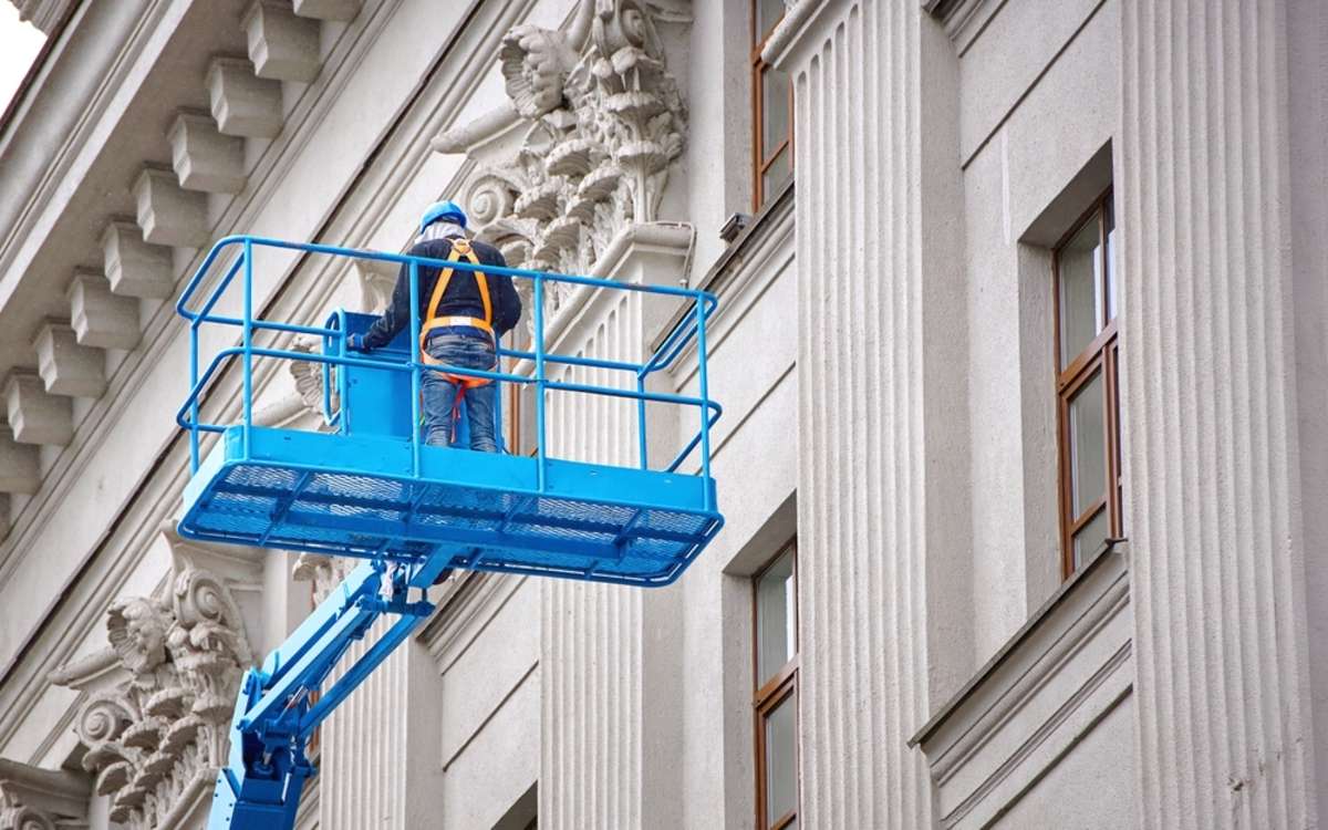 A worker checks the facade of a historic building, commercial property maintenance concept