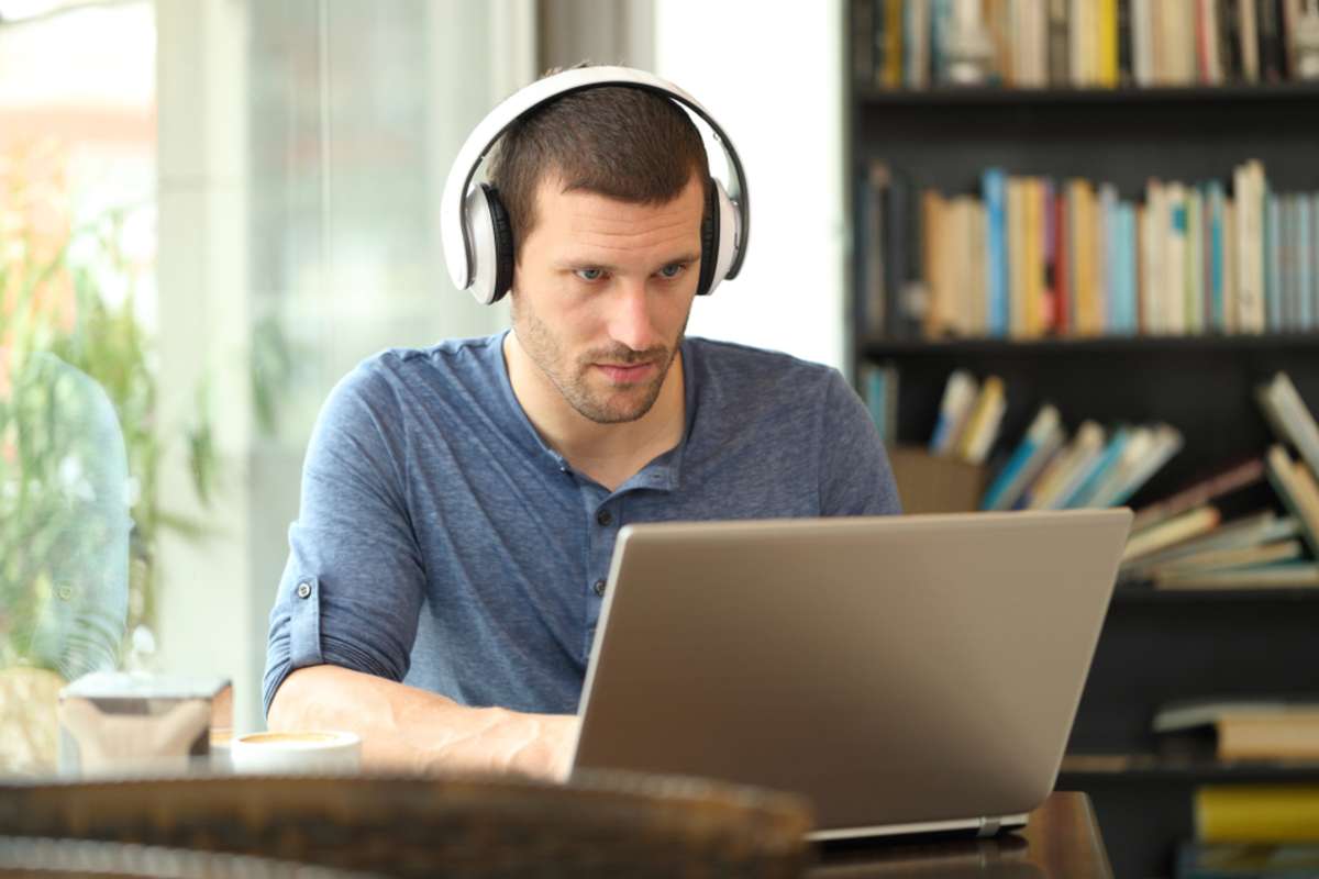 Man wearing headphones to watch an online course on a laptop, benefits of commercial real estate investment concept