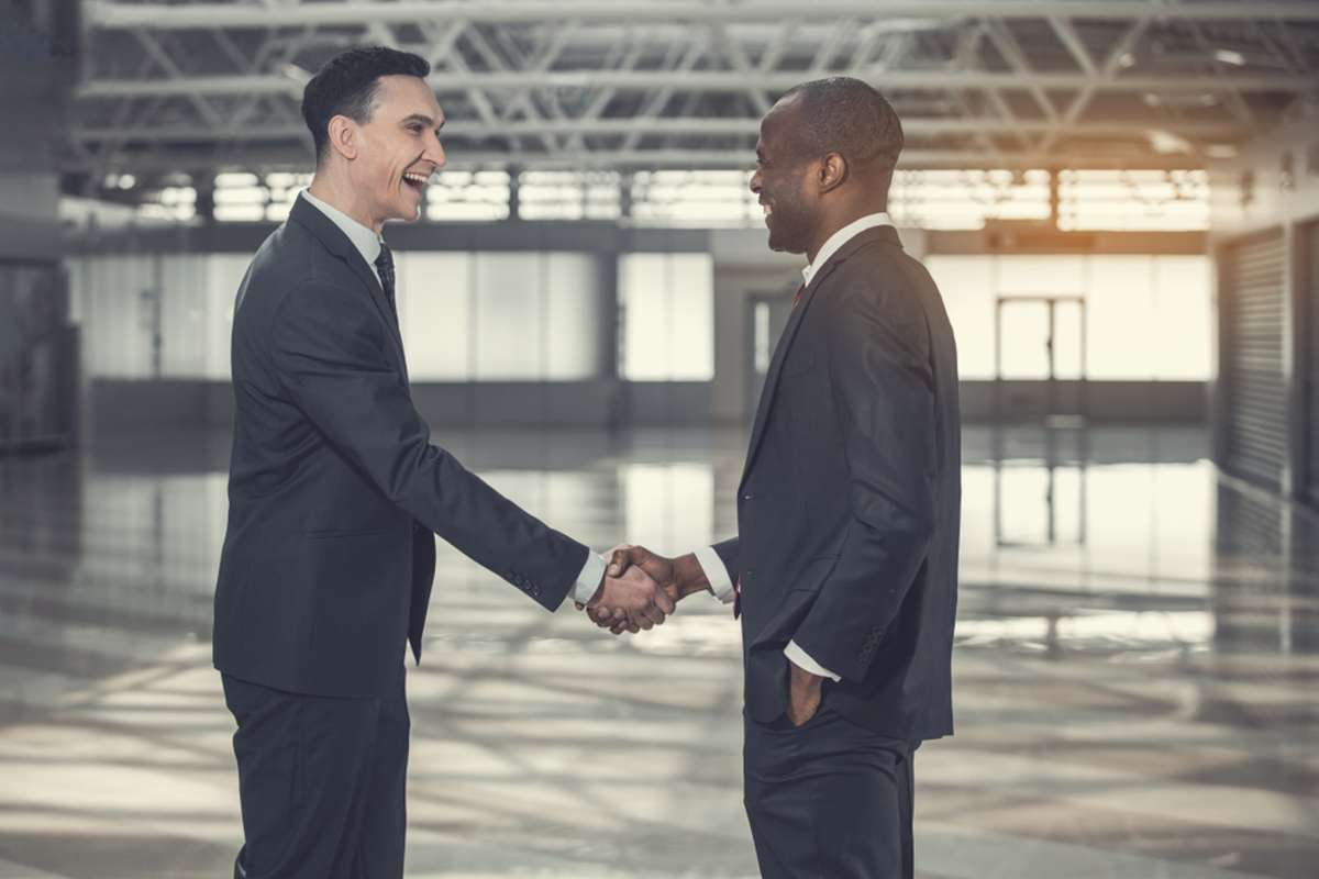 Two businessmen shake hands as successful commercial real estate investors