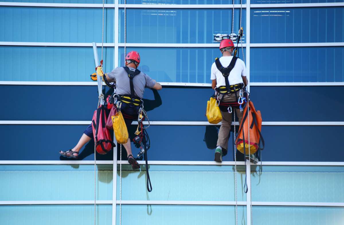 Window cleaners hang on a skyscraper, managed by commercial properties management